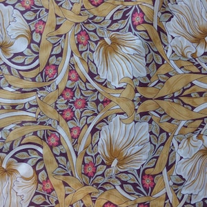 May include: A repeating pattern of stylised flowers and leaves in shades of brown, white, and pink on a dark purple background.