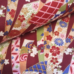 May include: Red fabric with a repeating pattern of gold, blue, and pink ribbons with floral designs. The fabric has a traditional Japanese aesthetic.