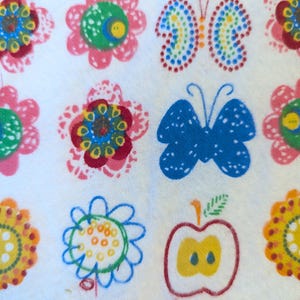May include: White fabric with a repeating pattern of colorful flowers, butterflies, and an apple. The flowers are in shades of pink, yellow, blue, and red. The butterflies are blue and multi-colored. The apple is red and yellow.