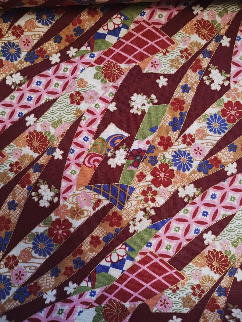 May include: Red fabric with a colourful Japanese-inspired pattern. The fabric features a variety of geometric shapes, flowers, and waves. The fabric is perfect for quilting, sewing, and crafting.
