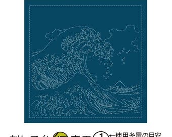 May include: A square, dark teal fabric with a white embroidered design of a large ocean wave, a mountain, and small boats. The Japanese text at the bottom indicates it is for sashiko thread.