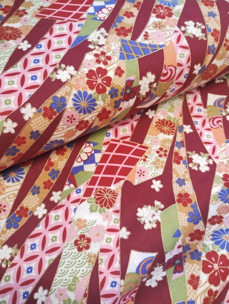 May include: Red fabric with a repeating pattern of colourful ribbons, flowers, and geometric shapes. The fabric has a traditional Japanese design.