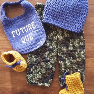 May include: A set of crocheted baby clothes in blue, green, and yellow. The set includes a hat, bib, pants, and booties. The bib has the text "FUTURE QUE" embroidered on it.