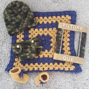 May include: A crochet set including a camouflage beanie, camouflage diaper cover with two gold buttons, a blue and gold granny square blanket, and tan booties with blue laces. A rectangular frame with camouflage sides and the text FUTURE QUE is included.