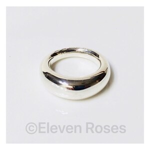May include: A silver ring with a smooth, rounded design. The ring is thick and has a polished finish.
