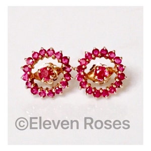 May include: A pair of gold earrings with a circle of ruby red stones around a smaller ruby red stone in the center.