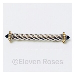 May include: A silver and gold twisted bar pin with black onyx ends. The pin is approximately 5 cm long.