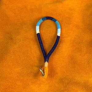 May include: A blue, white and black beaded key chain with a silver key ring. The key chain is looped into a circle shape.