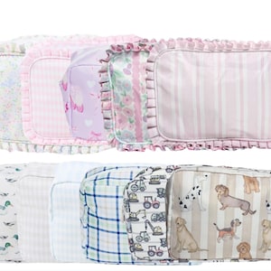 May include: A collection of rectangular cosmetic bags with various patterns. The top row features bags with floral, gingham, and heart prints, and a striped design. The bottom row includes bags with duck, plaid, construction vehicle, and dog patterns.