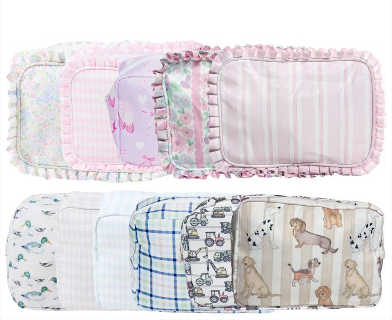 May include: A collection of rectangular cosmetic bags with various patterns. The top row features bags with floral, gingham, and heart prints, and a striped design. The bottom row includes bags with duck, plaid, construction vehicle, and dog patterns.