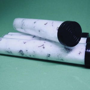 May include: Several clear plastic tubes filled with white material and dark specks, capped with black lids. The tubes are arranged on a green surface, with some tubes overlapping.
