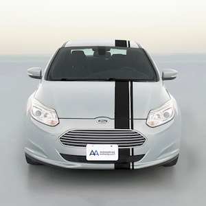 May include: Silver Ford car with black racing stripes running down the center of the hood and roof. The car has a license plate that reads "Automotive Authority LLC". The car is parked in front of a light background.