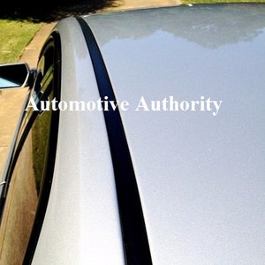 May include: A silver car with a black trim along the roofline. The trim has a carbon fiber pattern. The text "Automotive Authority" is visible on the car.