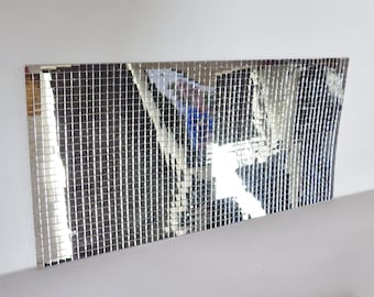 May include: A silver mosaic tile sheet with a reflective surface. The tiles are small and square, creating a grid pattern.