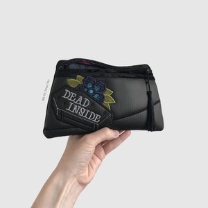 May include: Black zippered pouch with a black and green embroidered flower and the text "DEAD INSIDE" on a tombstone.