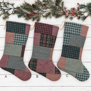 May include: Three Christmas stockings labeled A, B, and C, each featuring a patchwork design of various fabric squares in muted shades of forest green, burgundy, and charcoal gray. Each stocking includes a small fabric loop for hanging.