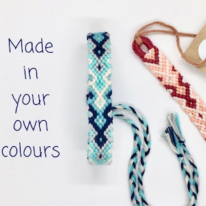 May include: Two friendship bracelets with a chevron pattern. One bracelet is blue, white, and gray. The other bracelet is red, pink, and white. The text "Made in your own colours" is written on a white background.