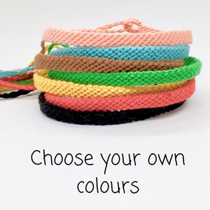 May include: A stack of colourful friendship bracelets in pink, blue, brown, green, yellow, orange and black. Choose your own colours.