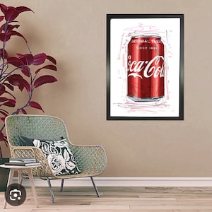 Può includere: Una stampa incorniciata di una lattina di Coca-Cola rossa con lettere bianche e le parole "Original Taste" e "Since 1886". La lattina è circondata da scarabocchi bianchi e rosa.