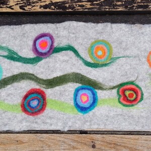 May include: A gray felt wall hanging with green, blue, and red circles with concentric rings. The circles are arranged in a wavy pattern.