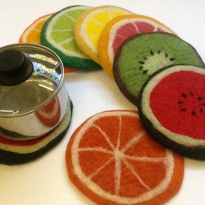 May include: Set of eight felt fruit-shaped pot holders. The pot holders are in the shape of a lime, lemon, grapefruit, kiwi, watermelon, and orange. The pot holders are all black on the bottom and have a white outline.