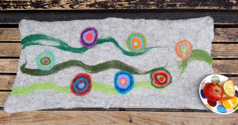 May include: A gray felt wall hanging with green, blue, and red circles with concentric rings. The circles are arranged in a wavy pattern.