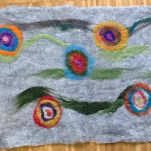 May include: A gray felt wall hanging with colorful circles and swirls. The circles are in shades of red, orange, yellow, green, blue, and purple. The swirls are in shades of green and black.