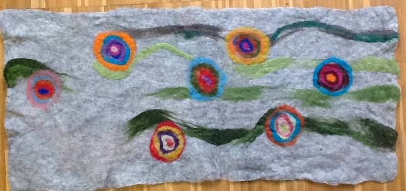 May include: A gray felt wall hanging with colorful circles and swirls. The circles are in shades of red, orange, yellow, green, blue, and purple. The swirls are in shades of green and black.
