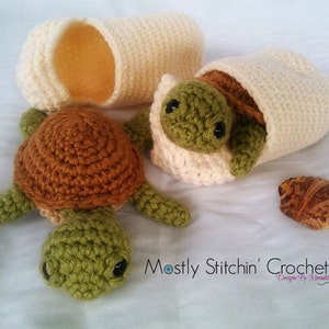 May include: Crocheted turtle toys in shades of green and brown, with a cream-colored egg. One turtle is emerging from the egg, another is lying beside it. A small shell is also present. The text "Mostly Stitchin' Crochet" is visible.