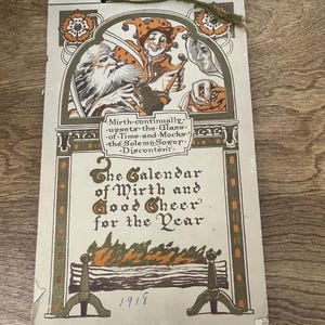 May include: Vintage 1918 calendar with a decorative illustration. The calendar features a jester and other figures in an arched frame, with text that reads "The Calendar of Mirth and Good Cheer for the Year". The calendar is cream-colored with brown and orange accents.