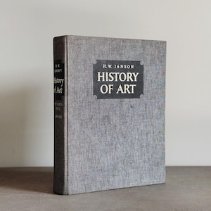 May include: A hardcover book titled "History of Art" by H.W. Janson. The book has a gray linen cover with the title in white letters on a black rectangular label. The spine also displays the title and author.