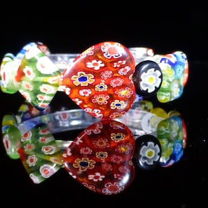 May include: A colourful glass bracelet featuring a heart-shaped charm. The charm is red with white and blue flowers. The bracelet is made from multiple glass beads in various colours and patterns.