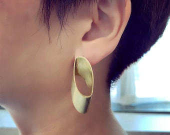 May include: A pair of gold oval-shaped earrings with a smooth, polished finish.