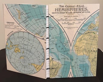 May include: A hand-bound journal featuring a vintage map cover titled The Century Atlas Hemispheres. The cover displays detailed geographical projections, including the Pacific and Atlantic Oceans, with black thread stitching along the spine.