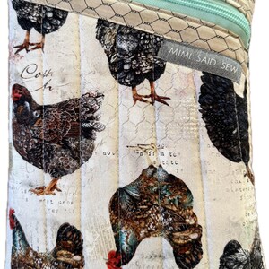 May include: A quilted pouch featuring a repeating pattern of chickens in shades of brown, black, and white. The pouch has a light blue zipper and a tag that reads "MIMI SAID SEW". The background has a vintage, handwritten script design.