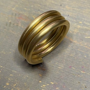 May include: A gold-coloured ring made of three stacked bands.