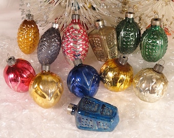 May include: A collection of vintage Christmas ornaments in various shapes and colors. The ornaments include pinecone, globe, and geometric designs in gold, red, blue, green, and silver. The ornaments are made of glass and have metal caps for hanging.