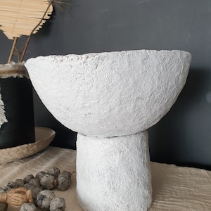 May include: White ceramic planter with a wide, round bowl and a cylindrical base. The planter has a rough, textured surface.