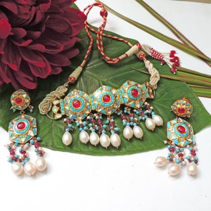 May include: A turquoise and red gemstone choker necklace with pearl and ruby accents. Matching earrings with turquoise and red gemstones.