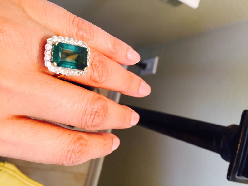 May include: A gold ring with a large emerald green gemstone surrounded by smaller diamonds.