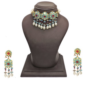May include: A gold choker necklace with turquoise and red stones, pearl drops, and matching earrings. The necklace and earrings are on a black display stand.