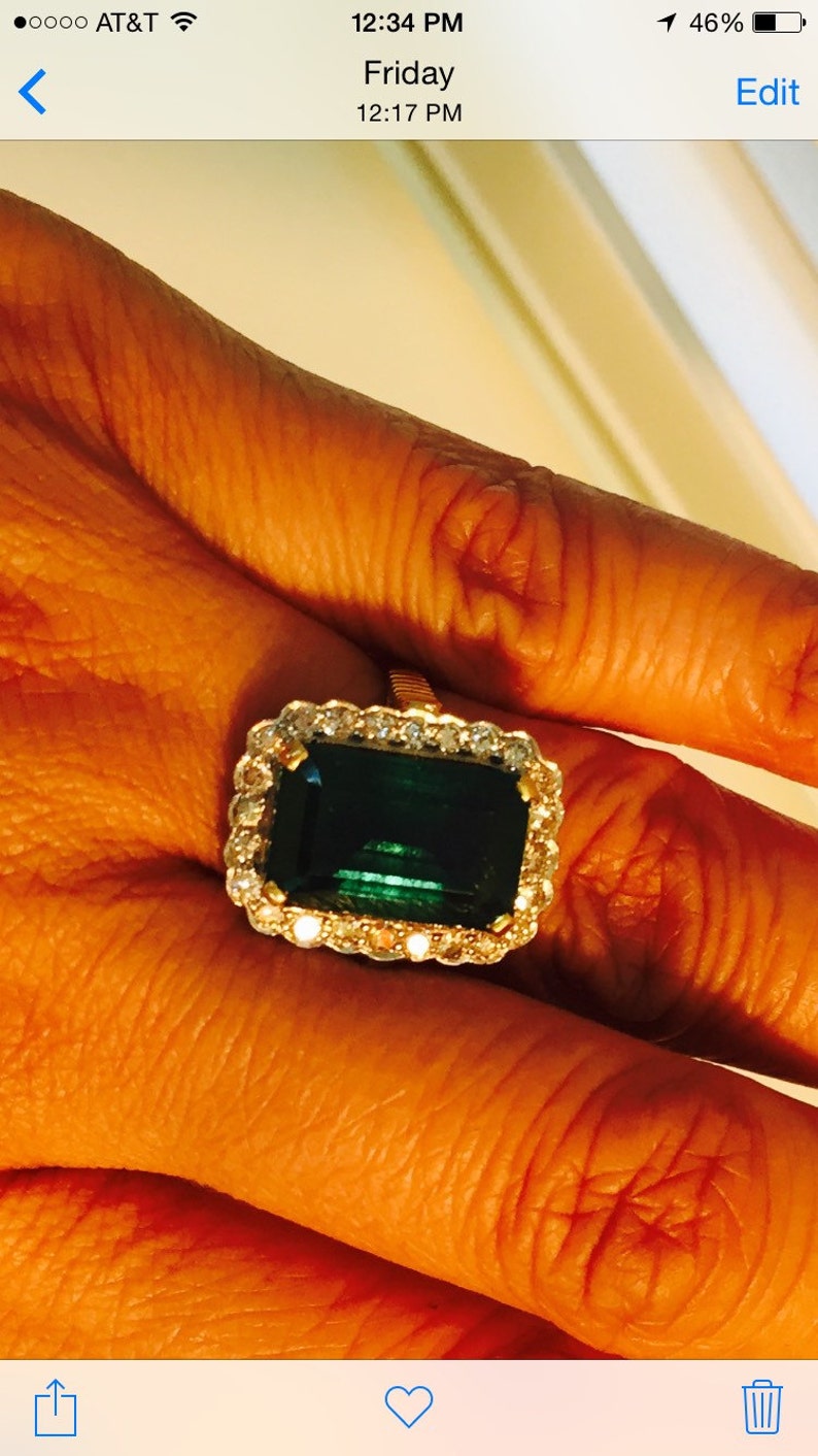 May include: A gold ring with a large emerald green gemstone surrounded by a halo of smaller diamonds.