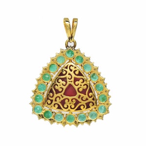 May include: A gold pendant featuring a red stone set within a filigree design, encircled by a border of green gemstones.