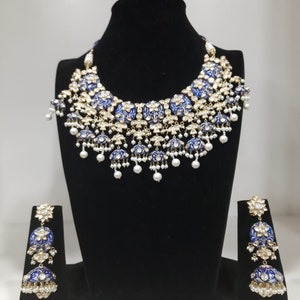 Pu&ograve; includere: Un set di collana e orecchini in smalto blu e bianco con accenti di perle. La collana &egrave; un pezzo importante con pi&ugrave; strati di ciondoli rotondi. Gli orecchini sono di design abbinato con tre ciondoli rotondi.