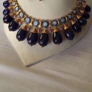 Pu&ograve; includere: Una collana d'oro con un designo in smalto blu e bianco e perle blu scuro a forma di lacrima. La collana &egrave; abbinata a orecchini abbinati con un design simile.