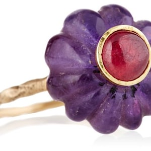 May include: A gold ring with a purple amethyst flower design and a red ruby center stone.