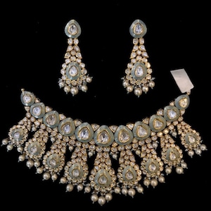 Pu&ograve; includere: Una collana in argento e oro con un design a forma di lacrima e accenti di perle. La collana &egrave; decorata con pietre blu e bianche. La collana &egrave; abbinata a orecchini coordinati.
