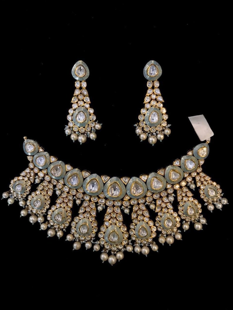 Pu&ograve; includere: Una collana in argento e oro con un design a forma di lacrima e accenti di perle. La collana &egrave; decorata con pietre blu e bianche. La collana &egrave; abbinata a orecchini coordinati.