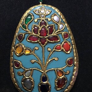 May include: A turquoise oval pendant with gold filigree and a floral design. The pendant is adorned with various gemstones, including rubies, emeralds, sapphires, and diamonds.
