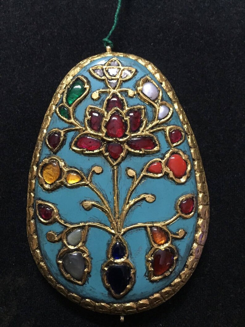 May include: A turquoise oval pendant with gold filigree and a floral design. The pendant is adorned with various gemstones, including rubies, emeralds, sapphires, and diamonds.